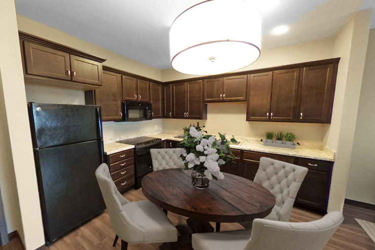 Dining area with wooden table, floral centerpiece, and warm kitchen cabinetry creating a welcoming space.